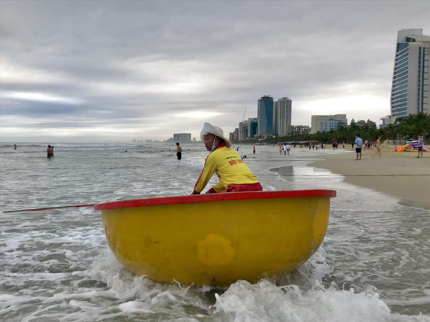 Nhân viên cứu hộ bơi thúng ra kêu gọi người tắm biển vào nơi an toàn