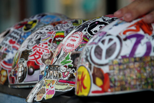 Những chiếc mũ bảo hiểm đầy màu sắc, được phủ kín bởi những miếng sitcker đầy màu sắc.