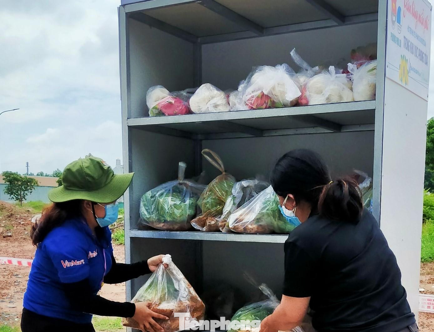 Lan Anh (áo xanh) chuẩn bị rau, củ, quả vào tủ cho người dân đến lấy