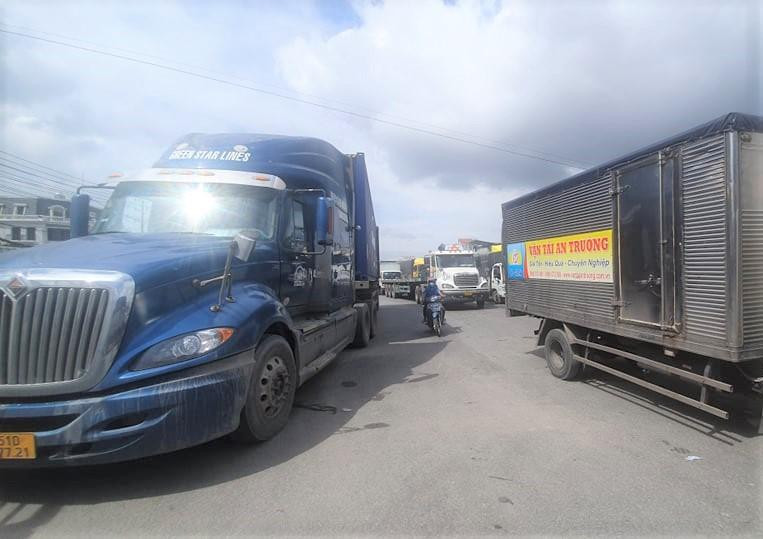 Xe máy xen giữa dòng xe tải để tìm cách thoát ra khỏi khu vực ùn tắc