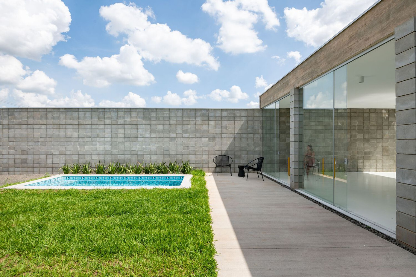 Ngôi nhà có bố cục mở và sử dụng tích hợp, được bao quanh bởi các tấm kính lớn.