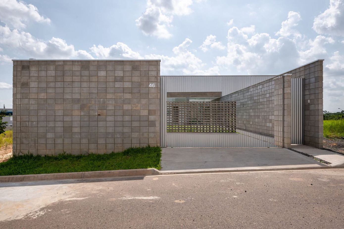 Phần phía trước của ngôi nhà được chia thành ba không gian lớn: Một không gian bê tông, đủ để đậu hai xe; một không gian khác bằng sỏi, nơi kiến trúc sư lắp đặt một thùng chứa đa năng; và cuối cùng là bãi cỏ lớn có hồ bơi.