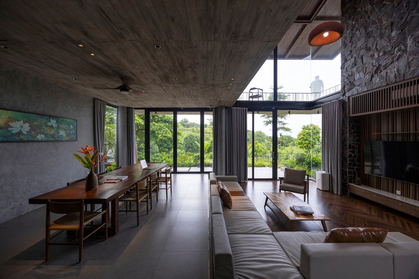 Bằng cách sử dụng toàn bộ tầng trệt làm không gian chung và đẩy các phòng ngủ lên tầng 2, thiết kế tạo ra các sân hiên và hành lang bên dưới đóng vai trò là không gian đệm, đảm bảo sự chuyển đổi tự nhiên của không gian bên ngoài vào không gian bên trong.