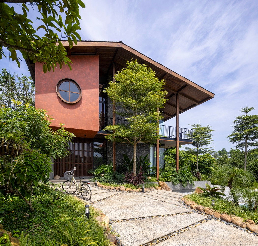 Công trình trong hình này nằm ở vùng đồi núi phía Tây Bắc ngoại ô Hà Nội, được bao quanh bởi những cánh rừng tự nhiên và mang đậm bản sắc văn hóa bản địa.