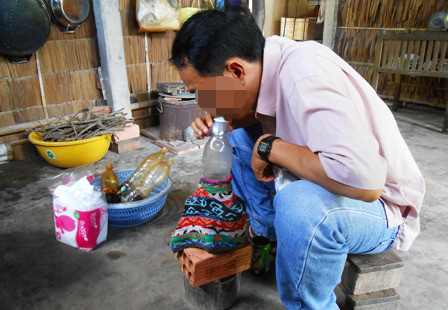 Một người khách đang ngậm cổ chai để hít hơi thuốc đang bốc lên. Một người khách đang ngậm cổ chai để hít hơi thuốc đang bốc lên