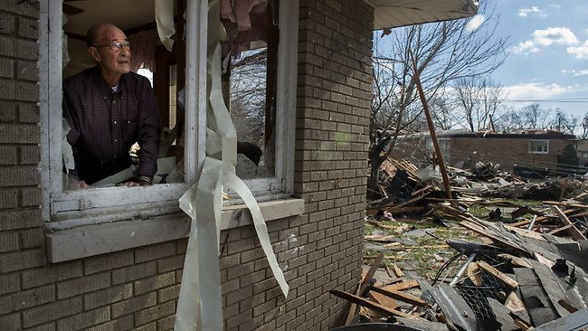 Người đàn ông nhìn qua cửa sổ cảnh đổ nát hoang toàn do bão gây ra ở Pekin, Illinois