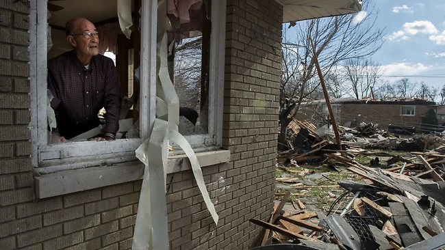 Người đàn ông nhìn qua cửa sổ cảnh đổ nát hoang toàn do bão gây ra ở Pekin, Illinois