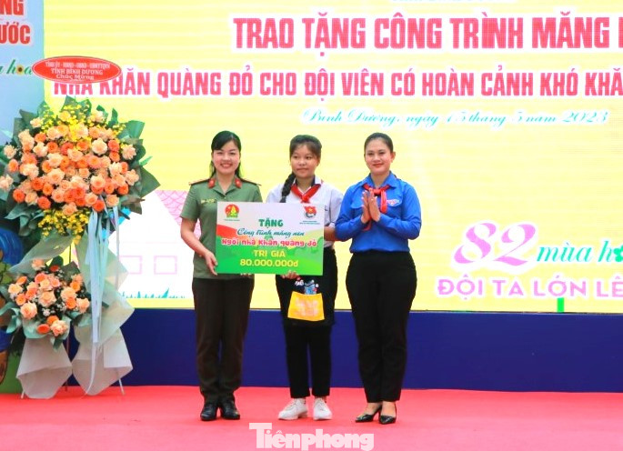 Bí thư Tỉnh Đoàn Bình Dương Trần Thị Diễm Trinh (bìa phải) và chị Hồ Thanh Thảo, Bí thư Đoàn thanh niên Công an tỉnh Bình Dương trao tặng bảng tượng trưng “Ngôi nhà khăn quàng đỏ” cho em Võ Thị Kiều My, học sinh lớp 8A7, trường THCS Bình Phú.