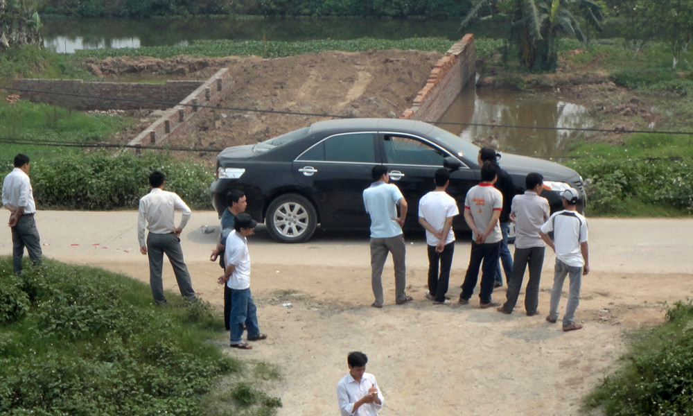 Người dân địa phương bên một chiếc xe bỏ lại hiện trường. Người dân địa phương bên một chiếc xe bỏ lại hiện trường