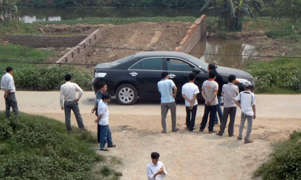 Người dân địa phương bên một chiếc xe bỏ lại hiện trường