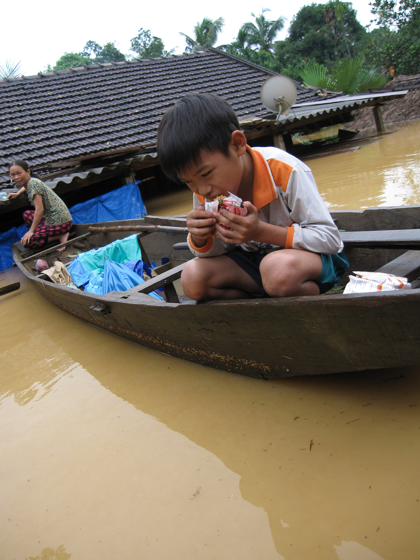 Vừa thấy đoàn cứu trợ tới, em Tuấn ỏ xã Gia Phố trượt từ trên nóc nhà xuống cầm gói mỳ ăn ngấu nghiến