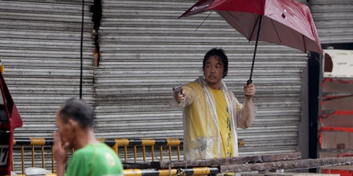 Một chủ cửa hàng cầm súng ngắn cảnh cáo những người cướp đồ. Ảnh: EPA Một chủ cửa hàng cầm súng ngắn cảnh cáo những người cướp đồ