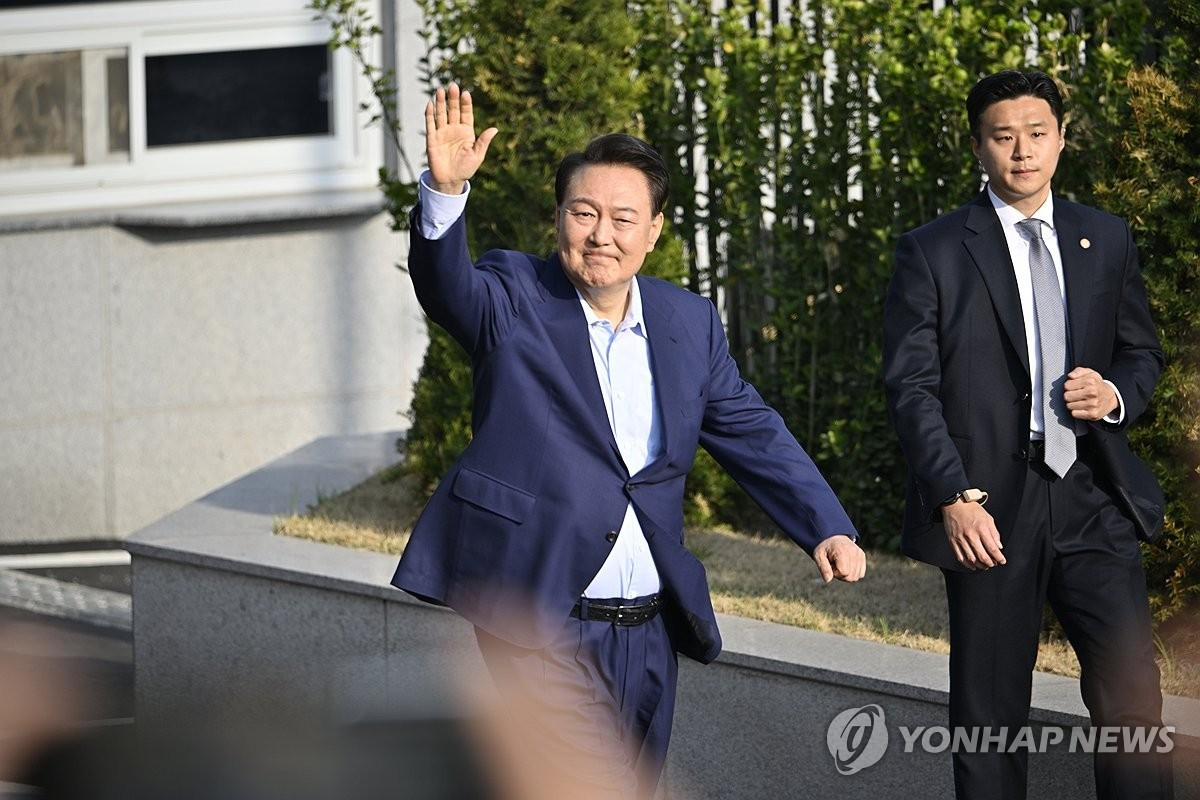 Ông Yoon vẫy chào người ủng hộ khi rời khỏi dinh thự tổng thống. (Ảnh: Yonhap)