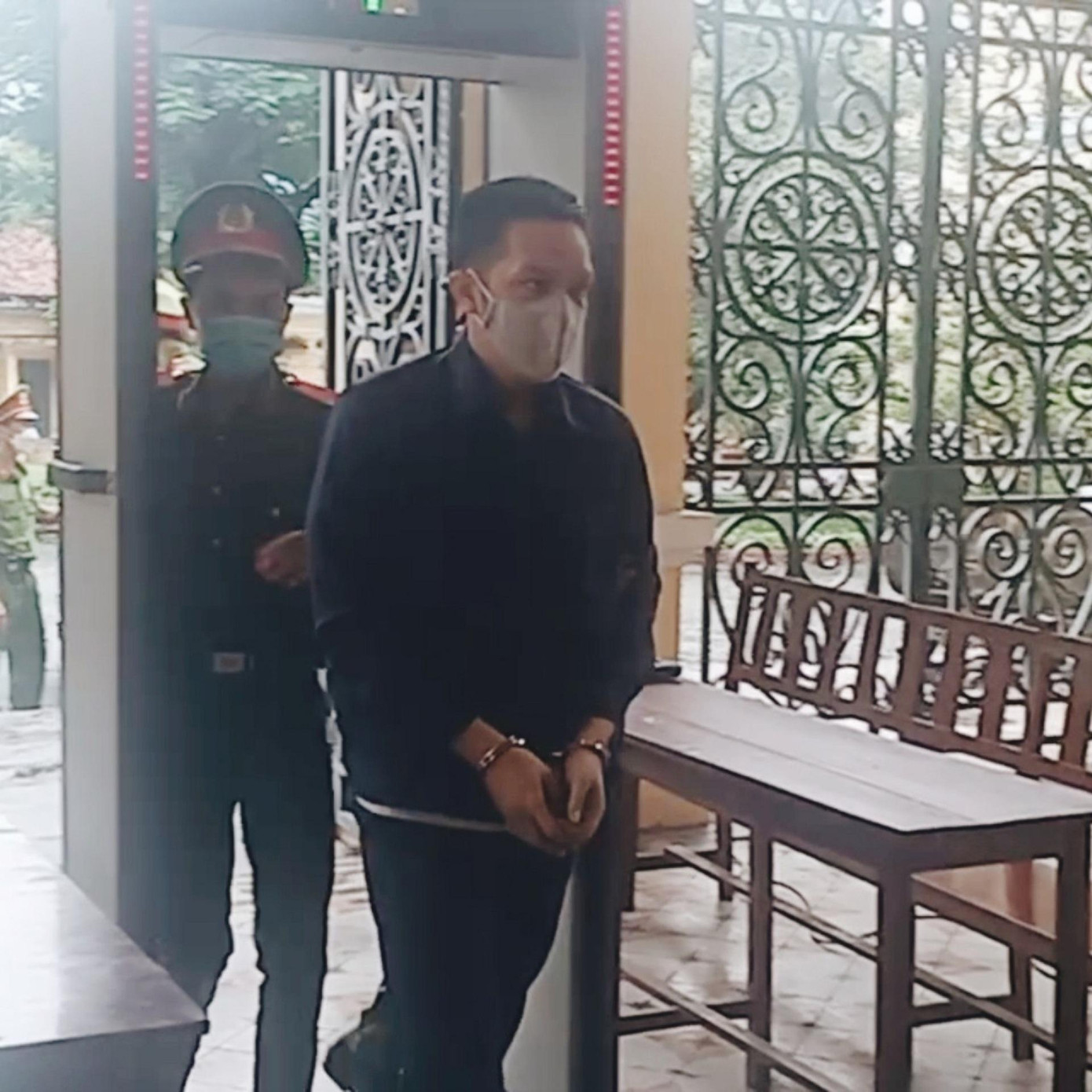 Cảnh sát dẫn giải Nguyễn Kim Trung Thái vào phòng xử án. Ảnh: Tân Châu