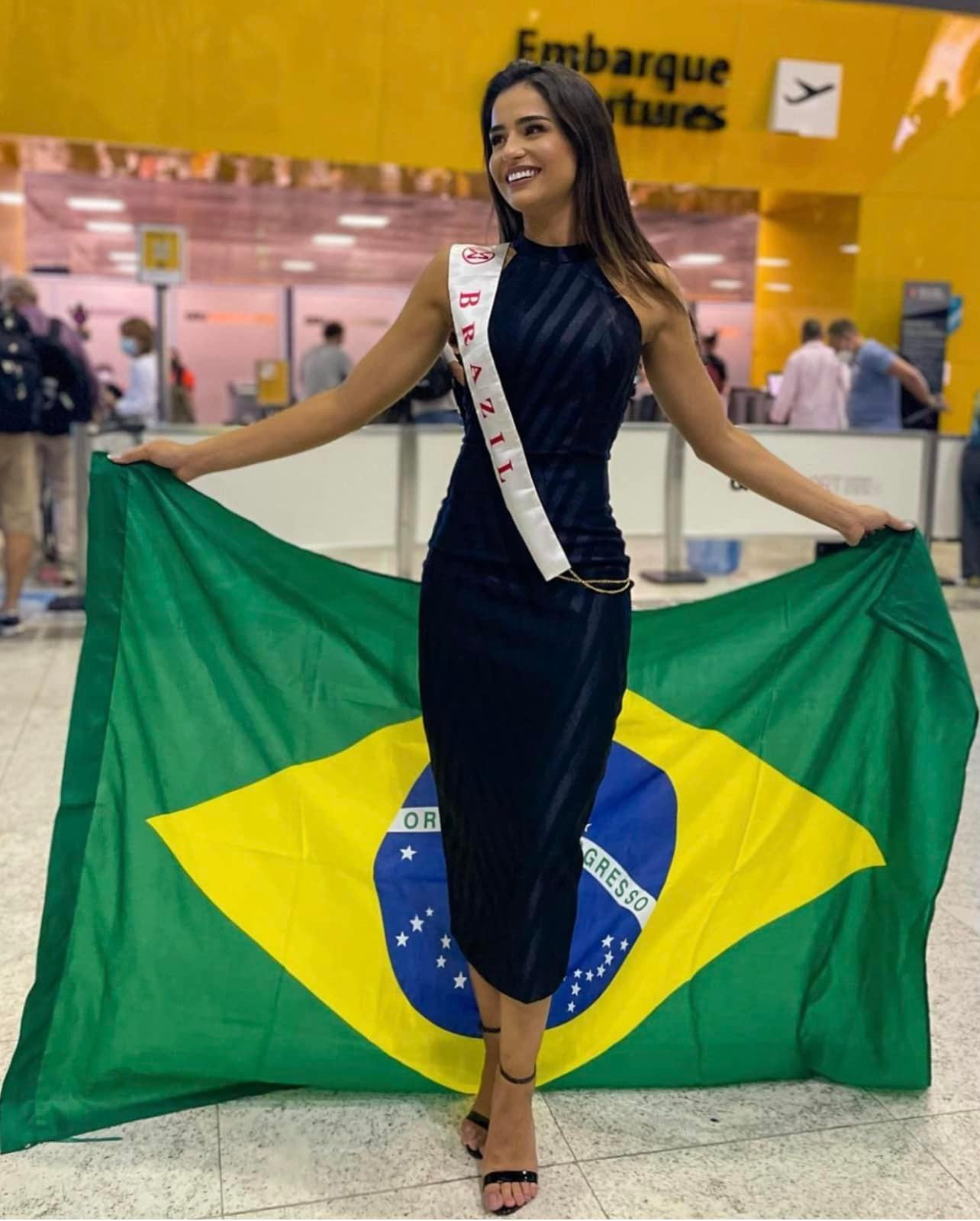 Hoa hậu Brazil diện váy đen bó sát, khoe dáng quyến rũ và không quên mang theo quốc kỳ ra sân bay.
