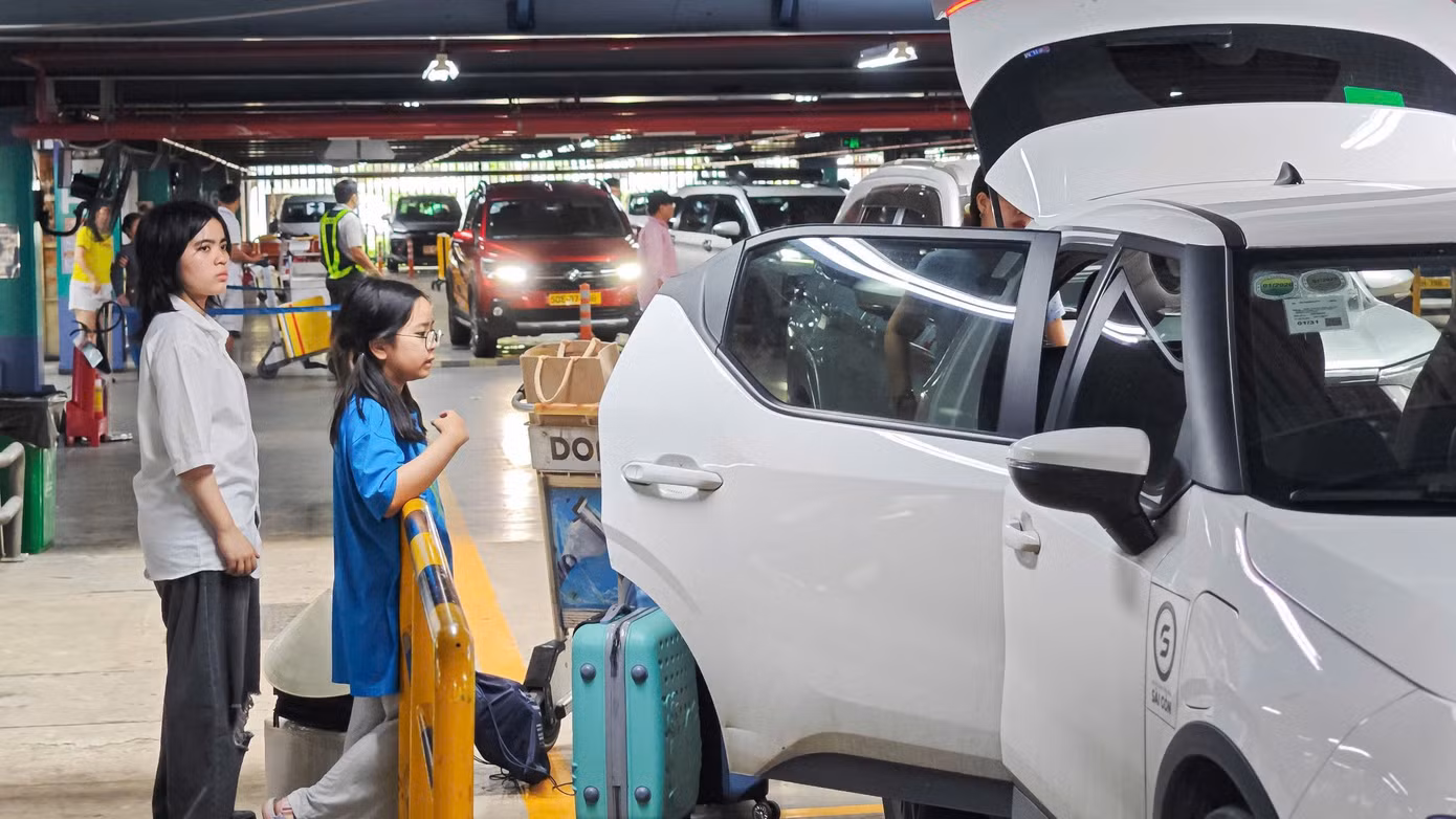 Tại khu vực chờ xe công nghệ, nhiều hành khách lỉnh kỉnh hành lý chờ xe.