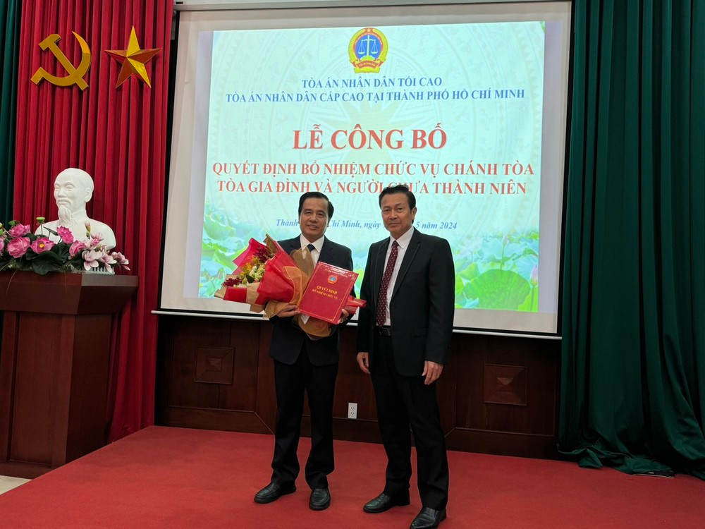 Ông Trần Văn Châu, Chánh án TAND cấp cao tại TPHCM (phải) trao quyết định và tặng hoa chúc mừng ông Trần Văn Mười.