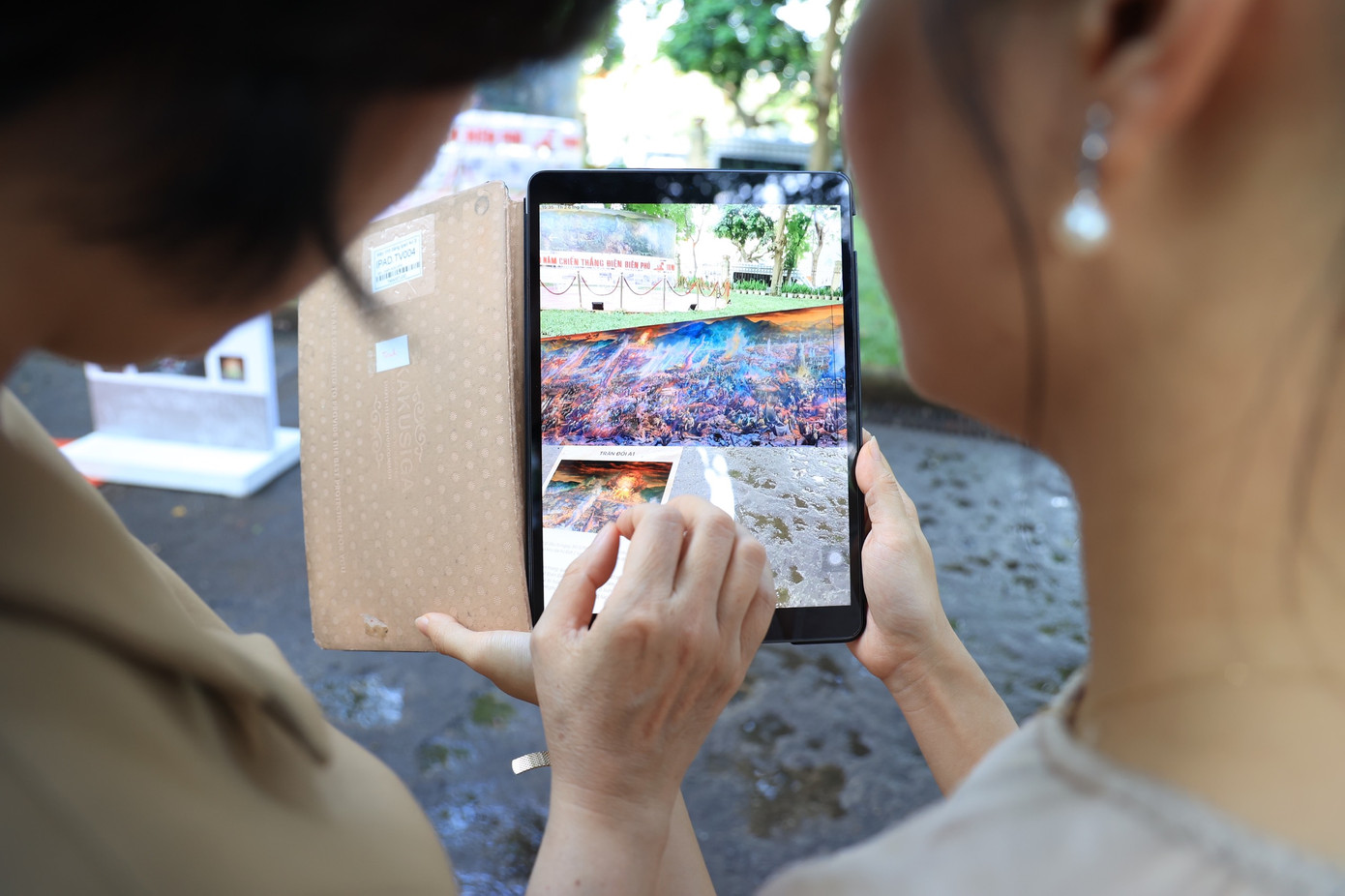 Du khách sử dụng điện thoại, máy tính bảng quét mã QR và trải nghiệm công nghệ AR ẩn trong bức tranh.