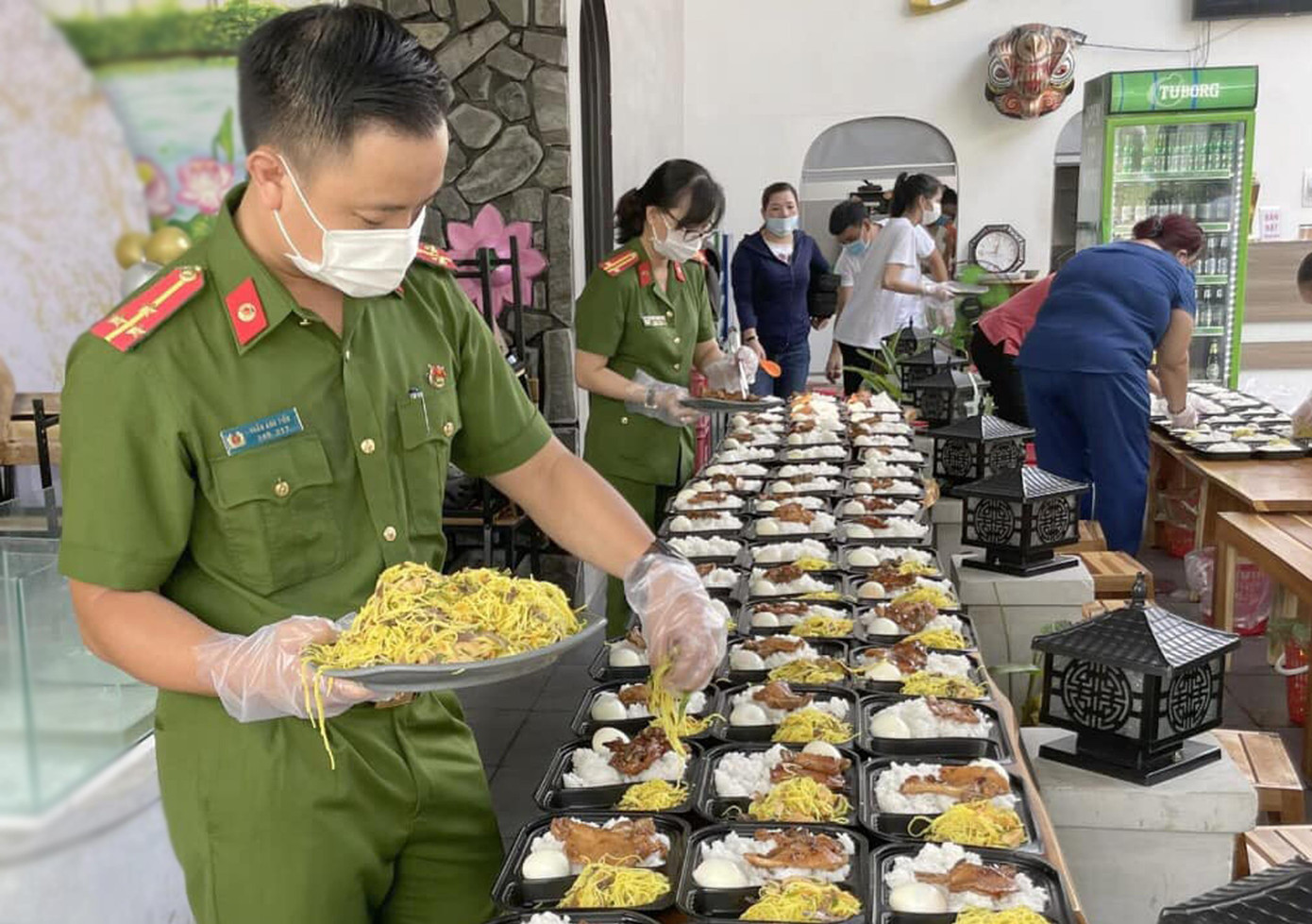 Bên cạnh đó, cán bộ chiến sĩ cùng trực tiếp đi chợ và vào bếp chế biến những suất cơm trao tặng đồng đội làm nhiệm vụ ở các chốt kiểm soát dịch, ở khu vực cách ly... và những người dân trên đường hồi hương. Trong đó, có &quot;Bữa cơm yêu thương mùa COVID&quot;, &quot;Bữa cơm yêu thương&quot;, &quot;Bữa cơm hương vị gia đình&quot;... - Ảnh: Đoàn viên thanh niên Công an tỉnh Thừa Thiên - Huế chuẩn bị bữa cơm yêu thương gửi đến đồng đội