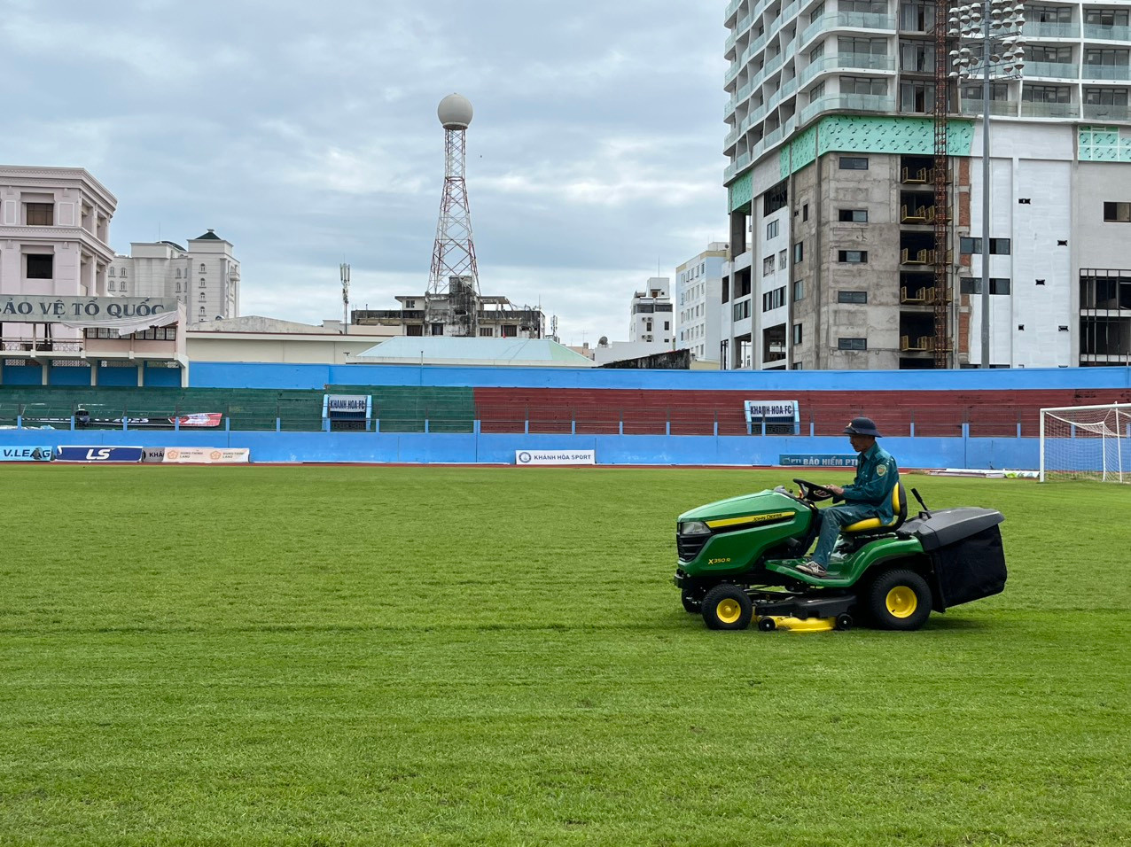 Công nhân cho máy cắt lại cỏ trên sân 19/8. Ảnh L.H Công nhân cho máy cắt lại cỏ trên sân 19/8. Ảnh L.H