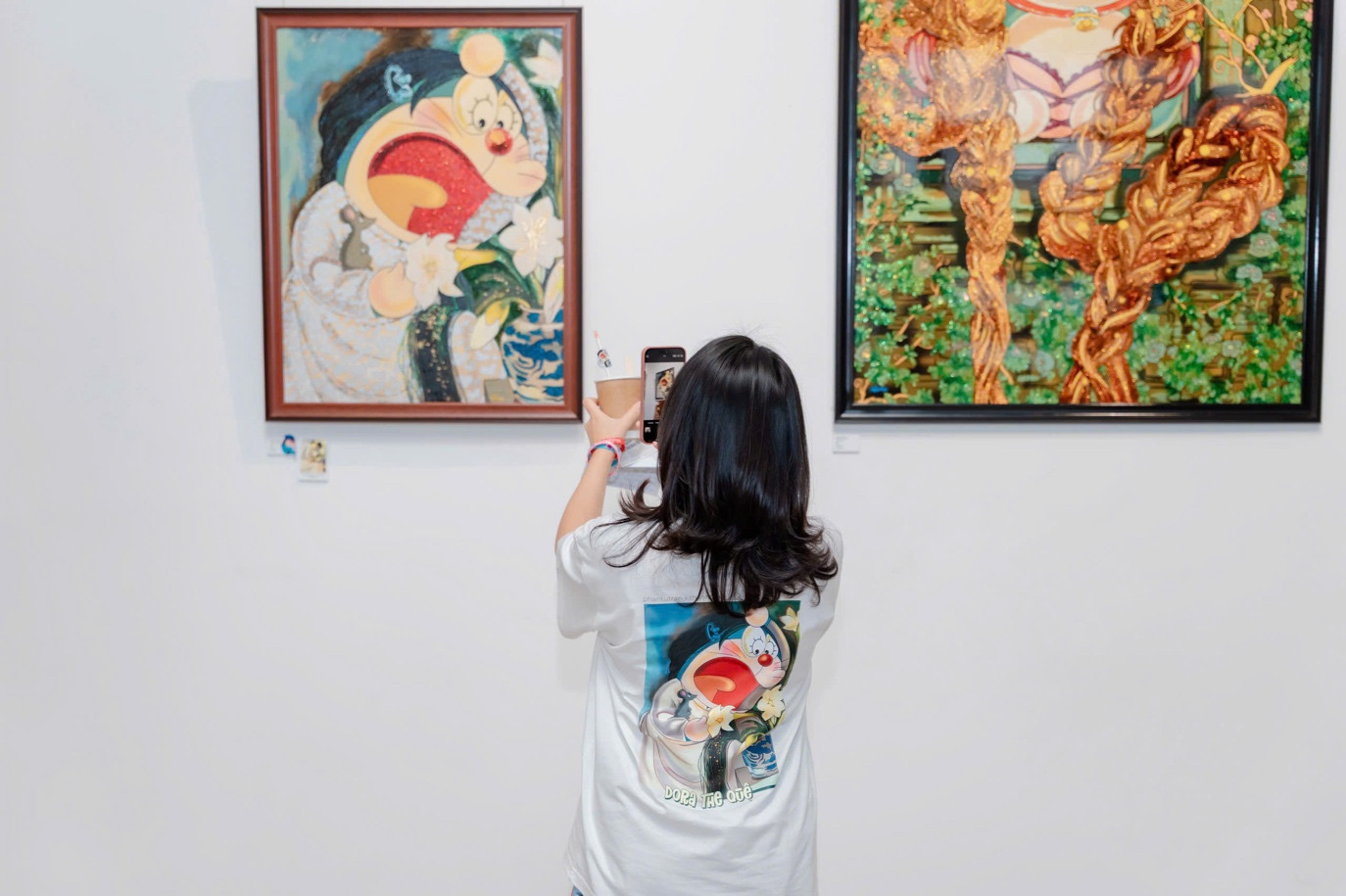 Khách tham quan diện áo in hình tranh Doraemon phái sinh, ghi lại khoảnh khắc tại triển lãm Tái Sinh.