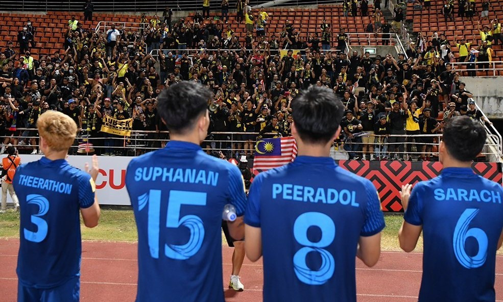 CĐV Malaysia khích lệ Thái Lan dù đội nhà thua trên sân Thammasat. (Ảnh: Main Stand) CĐV Malaysia khích lệ Thái Lan dù đội nhà thua trên sân Thammasat. (Ảnh: Main Stand)