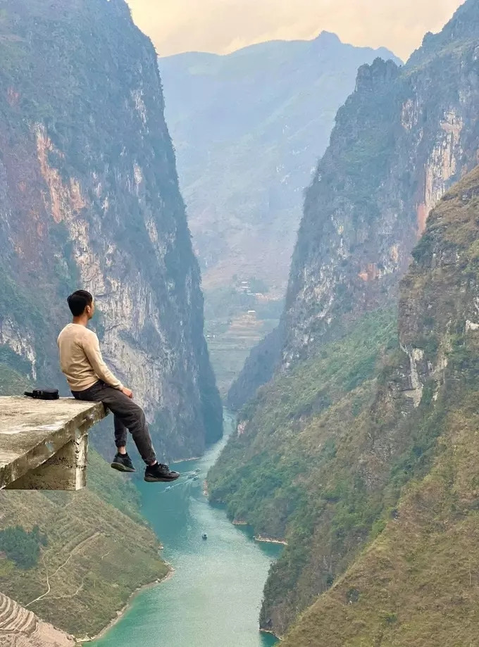 Du khách ngồi chơi vơi trên lan can bê tông, phía trước là cảnh sông Nho Quế hùng vĩ. (Ảnh: Nguyễn Tiệp) Du khách ngồi chơi vơi trên lan can bê tông, phía trước là cảnh sông Nho Quế hùng vĩ. (Ảnh: Nguyễn Tiệp)