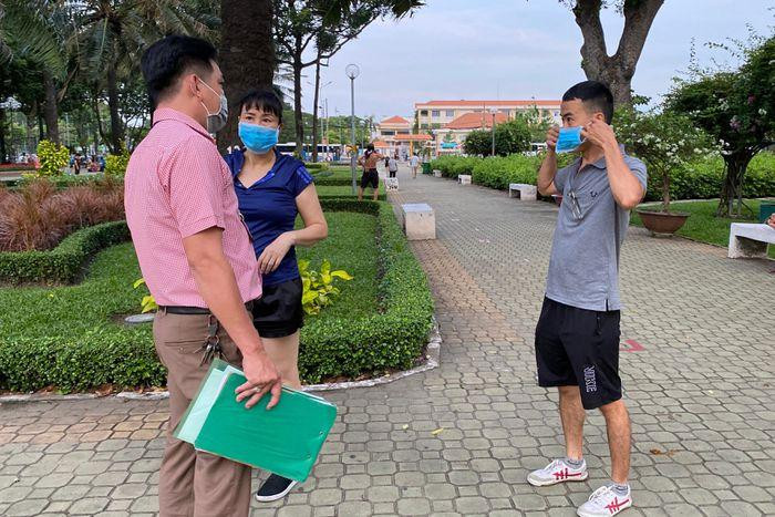 Khi bị tổ công tác nhắc nhở, nam thanh niên mới lấy khẩu trang từ trong người mang vào. (Ảnh: An Huy)