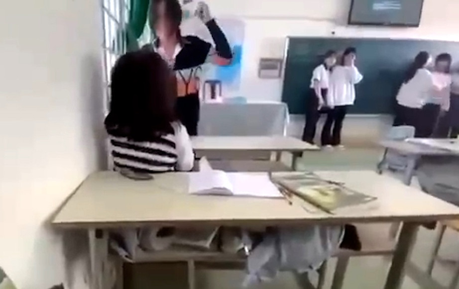 Nữ sinh mang theo dụng cụ chích điện dọa và liên tiếp đánh bạn ngay trong lớp. (Ảnh cắt từ clip) Nữ sinh mang theo dụng cụ chích điện dọa và liên tiếp đánh bạn ngay trong lớp. (Ảnh cắt từ clip)