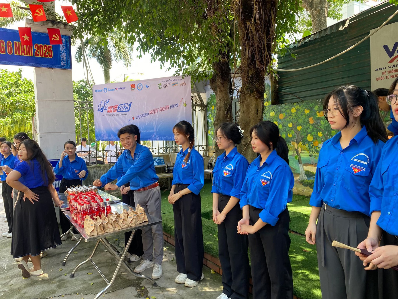 Biệt đội áo xanh che ô, phát nước cho thí sinh làm thủ tục dự thi tại điểm trường THPT Nguyễn Thị Minh Khai.