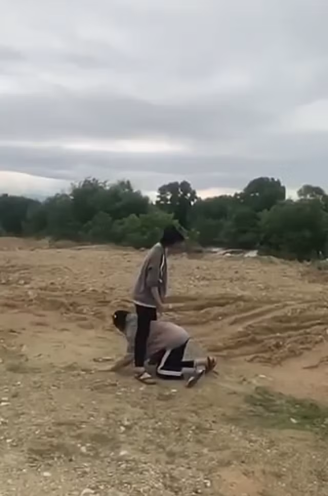 Sau khi đánh bạn, nữ sinh mang áo xám bắt bạn nữ kia chui vào giữa 2 chân.