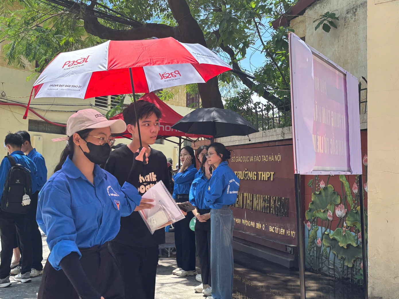 Biệt đội áo xanh che ô, phát nước cho thí sinh làm thủ tục dự thi tại điểm trường THPT Nguyễn Thị Minh Khai.