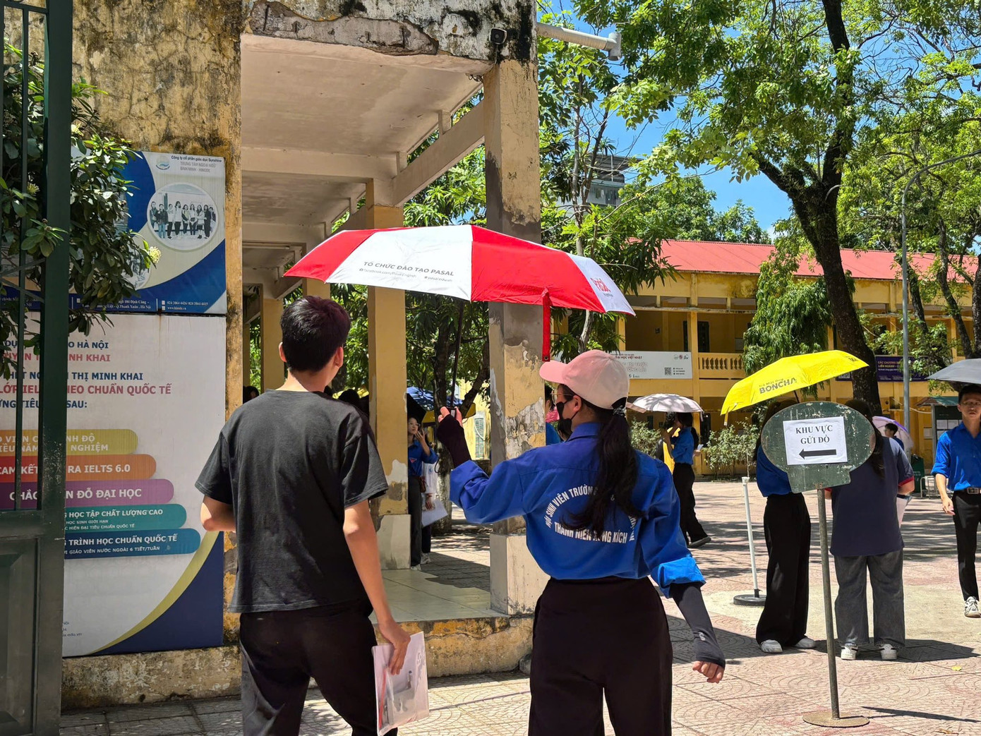 Biệt đội áo xanh che ô, phát nước cho thí sinh làm thủ tục dự thi tại điểm trường THPT Nguyễn Thị Minh Khai.