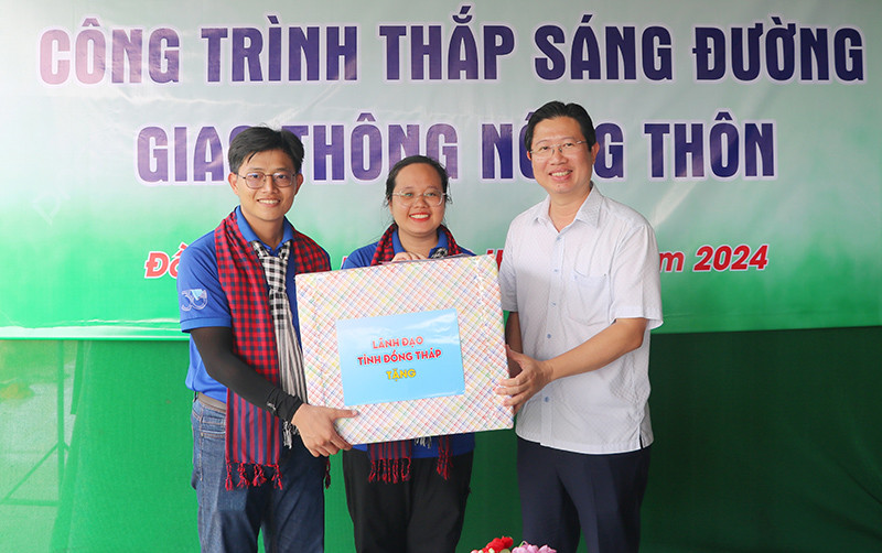 Đại diện các sinh viên tình nguyện Đại học Khoa học Tự nhiên - Đại học Quốc gia TP.HCM nhận quà từ Phó Chủ tịch UBND tỉnh Đồng Tháp Huỳnh Minh Tuấn (bìa phải) trao tặng.