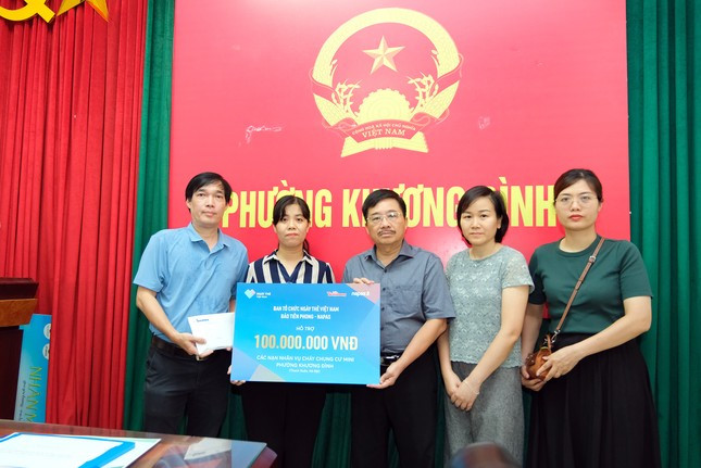 Đại diện ban Tổ chức Ngày Thẻ Việt Nam, nhà báo Vũ Tiến, Phó Tổng Biên tập báo Tiền Phong (đứng thứ 3 từ phải sang), trao hỗ trợ cho nạn nhân trong vụ cháy chung cư tại phường Khương Đình. (Ảnh: Mạnh Thắng)