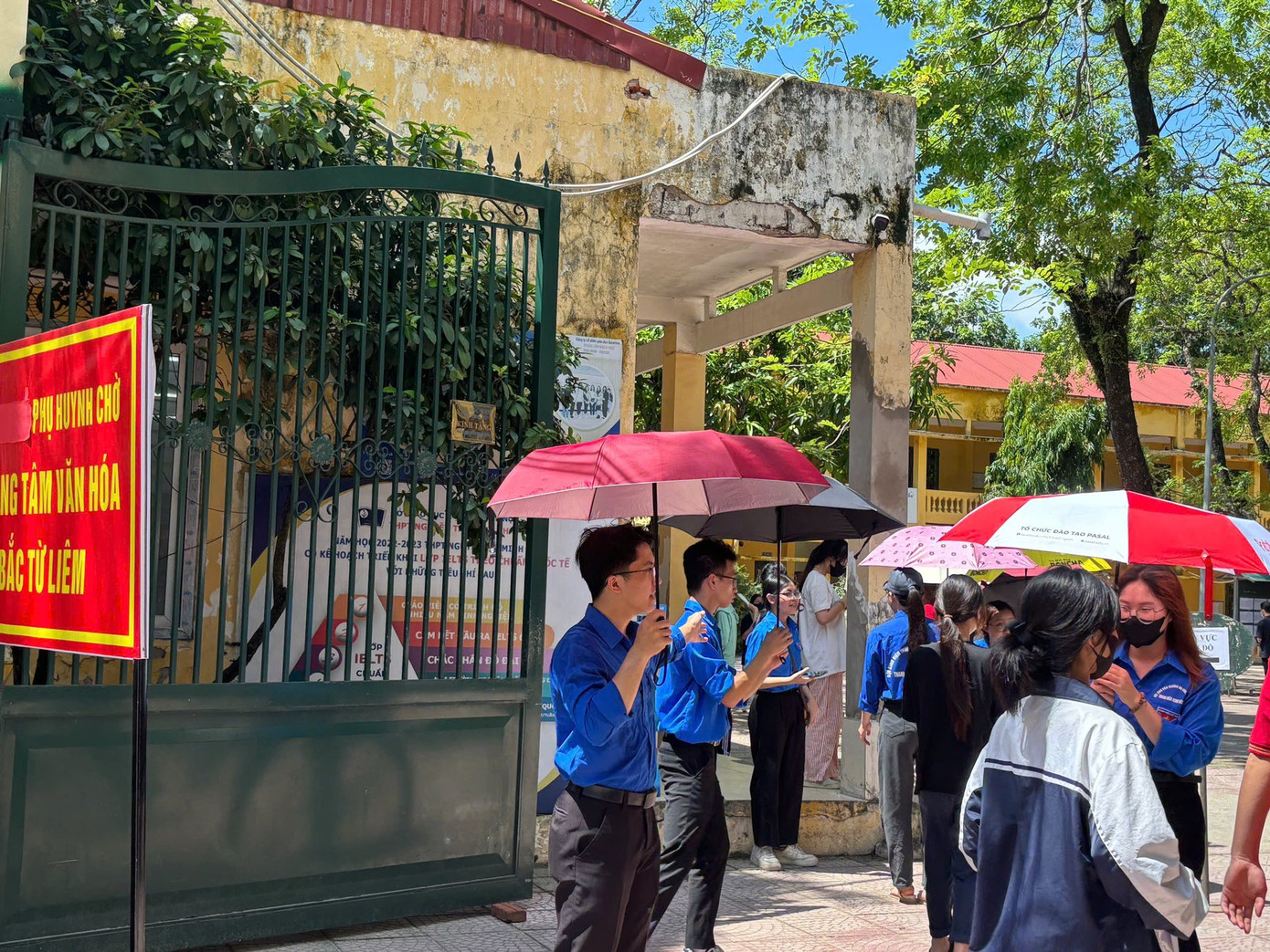 Biệt đội áo xanh che ô, phát nước cho thí sinh làm thủ tục dự thi tại điểm trường THPT Nguyễn Thị Minh Khai.