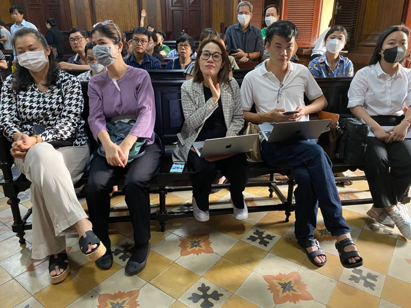 Tòa bố trí báo chí và người có nghĩa vụ, quyền lợi liên quan ngồi chung phòng và theo dõi phiên xử qua màn hình.