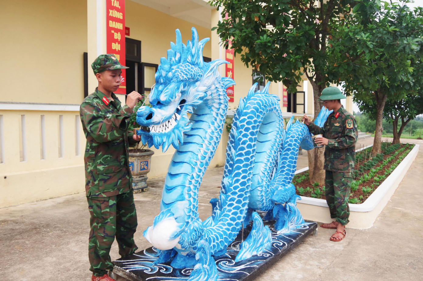Tổ gồm 3 đồng chí: Trung sĩ Cao Quang Long Vũ, Tiểu đội trưởng Tiểu đội 2, Trung đội 7 - đảm nhiệm vẽ và thiết kế mô hình, trang trí; Binh nhất Nguyễn Quốc Huy, chiến sĩ Tiểu đội 2, Trung đội 7 - đảm nhiệm làm hồ, đắp xi măng; Binh nhất Trương Quốc Đạt, chiến sĩ Tiểu đội 5, Trung đội 8 - trang trí, sơn màu. Ảnh: Ngọc Tú
