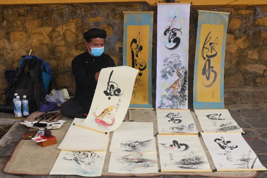 Dưới bóng cây xanh bên bờ sông Hoài hướng về phía chùa Cầu, người ta lại bắt gặp hình ảnh quen thuộc, "ông đồ" mặc áo dài với khăn vấn trên đầu, bày mực giấy say sưa ngồi viết thư pháp, cho chữ những người đi chùa cầu lộc. "Ông đồ" là Trịnh Văn Vương, 38 tuổi, quê ở xứ Thanh Hà, Quảng Nam. Xuân này, "đồ Vương" đã có 20 năm viết thư pháp tại chùa Cầu - ảnh T.H