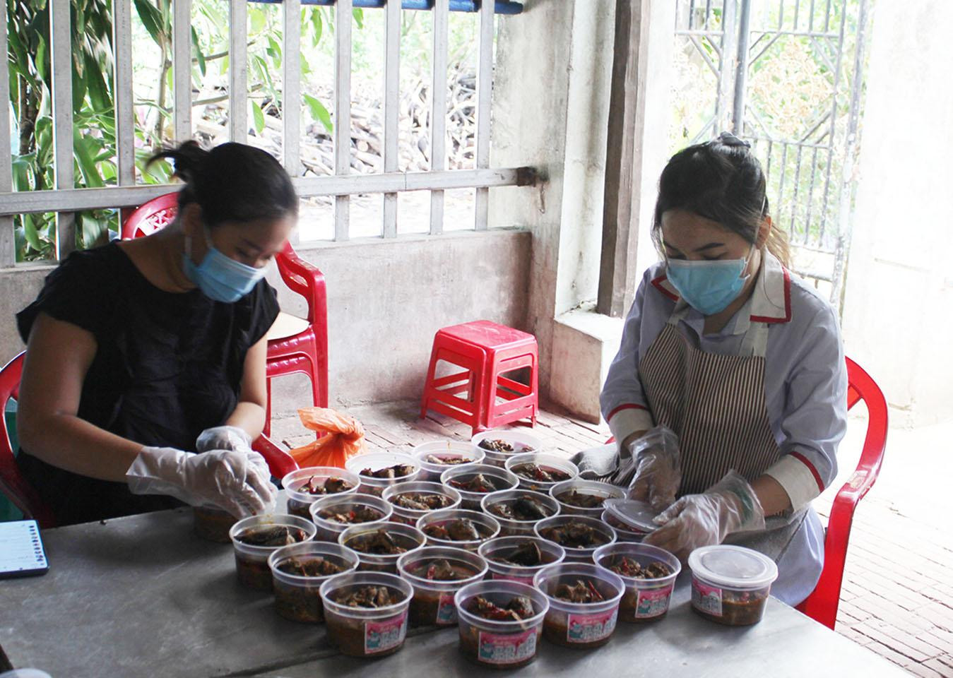 Trong căn nhà nhỏ của gia đình, hai chị mang khẩu trang, đeo găng tay và giữ khoảng cách an toàn suốt quá trình sơ chế cá, cho đến tẩm ướp, nấu nướng, đóng hộp - Ảnh: H.O
