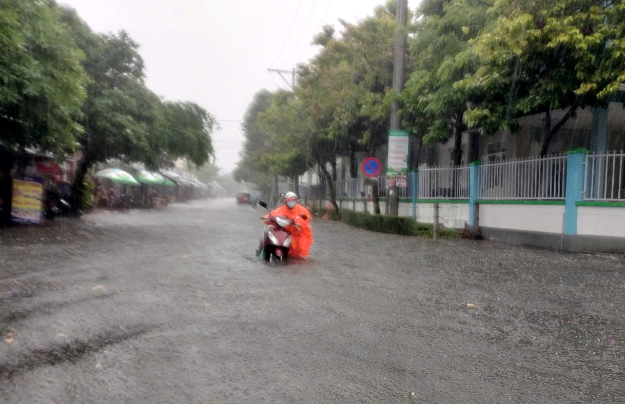 Người và phương tiện khổ sở di chuyển trong mưa.