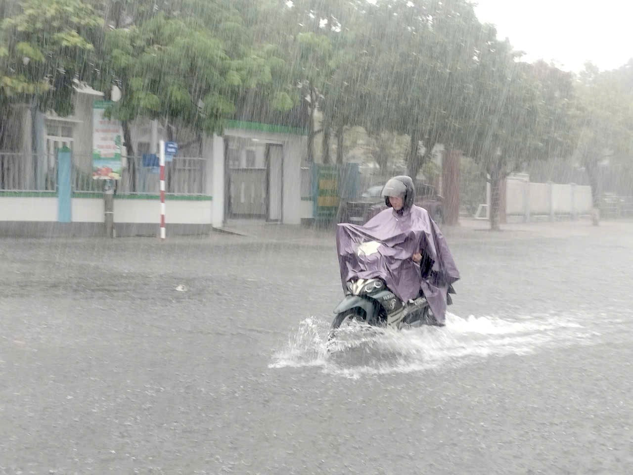 Người và phương tiện khổ sở di chuyển trong mưa.