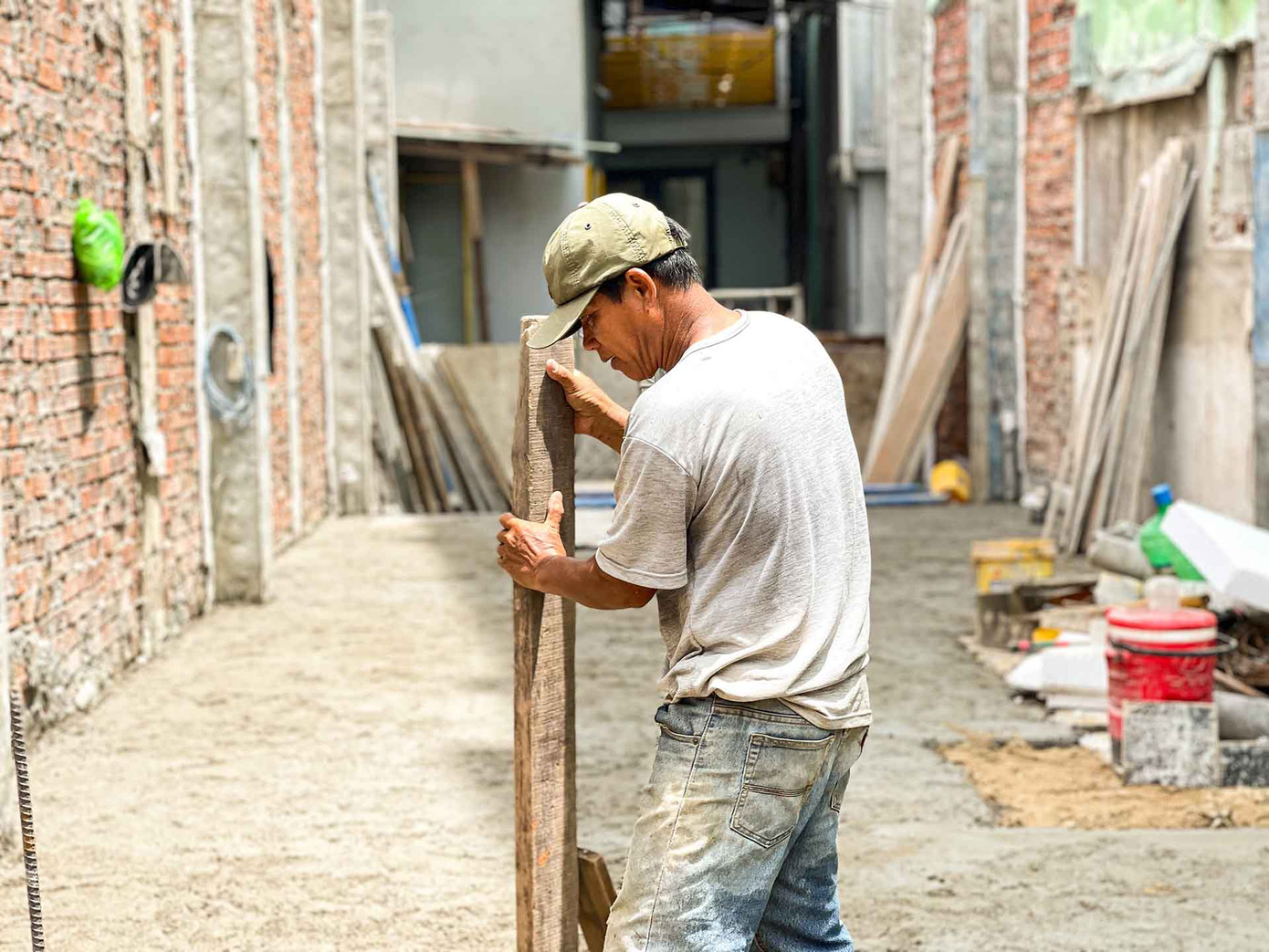 Bên cạnh đó là anh Hồ Duy, 42 tuổi, một phụ hồ đang cật lực làm công việc trộn bê tông. "Thời tiết thế này ai cũng muốn ở nhà, nhưng ở nhà thì tiền đâu để chăm lo cho gia đình. Nghĩ đến điều đó thì dù có nắng mưa cỡ nào cũng không làm khó được tôi” - anh Duy chia sẻ. (Ảnh: Thanh An)