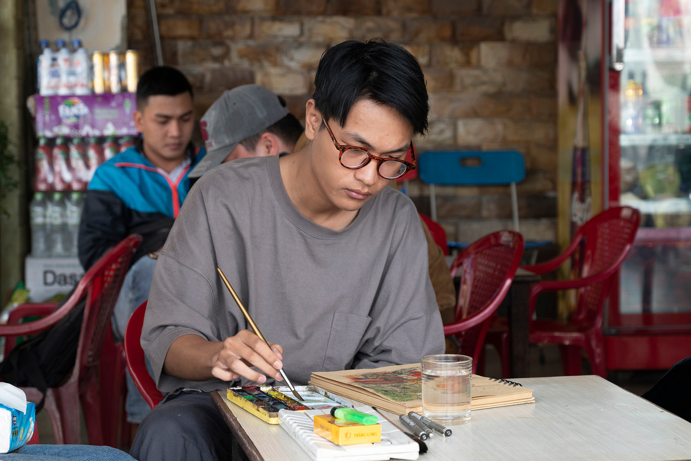 Thạch hoàn thành những công đoạn cuối cùng của bức ký họa nơi quán cà phê cóc đầu đường Nguyễn Thái Học (Ảnh: Huỳnh Như)