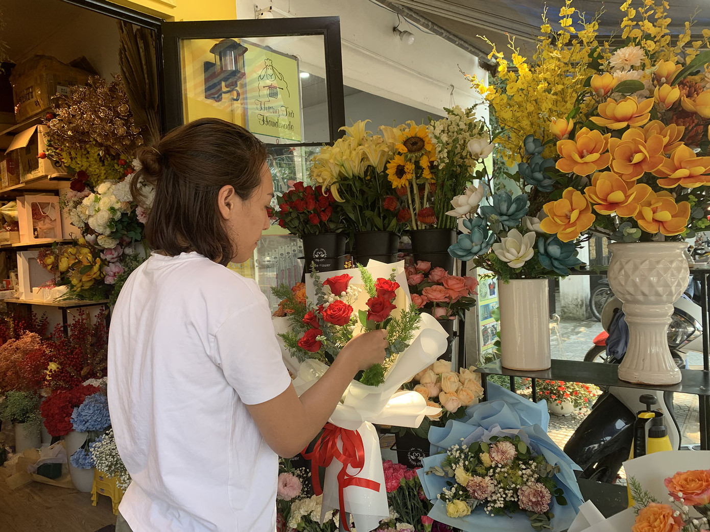 Chị Tâm đang gấp rút cắm hoa để kịp giao cho các khách đặt online. - Ảnh: Khánh - Hà