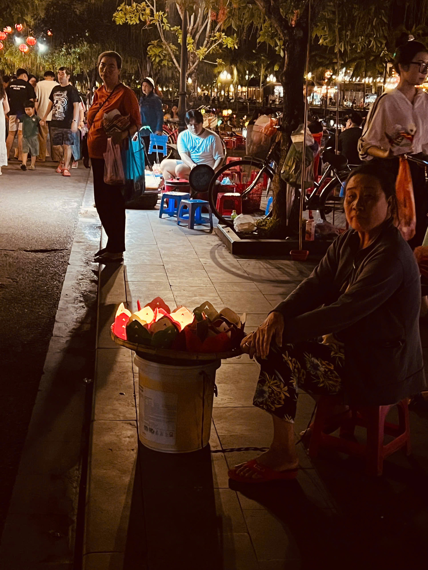 Những phụ nữ bán hoa đăng lặng lẽ ngồi chờ khách ghé mua. Ảnh: Văn Nhất