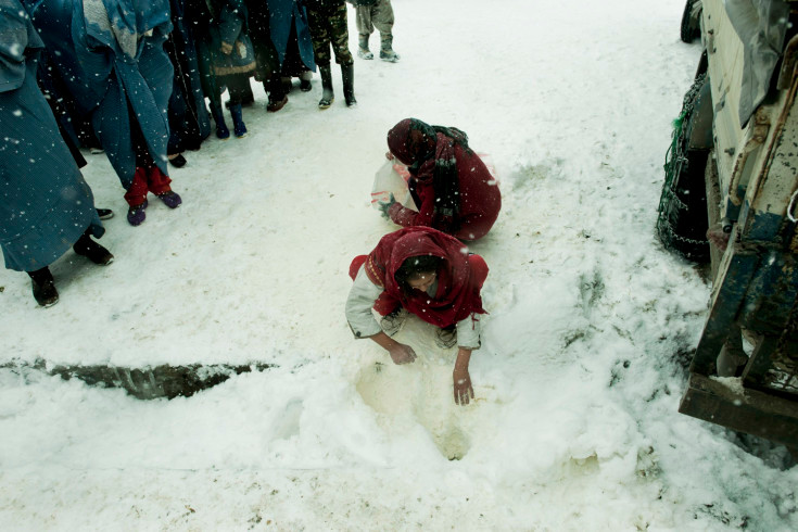 Những người phụ nữ cố gắng vớt vát lại bột mì bị đổ trên tuyết ở trại tị nạn Charahi Qambar, Kabul, Afghanistan.