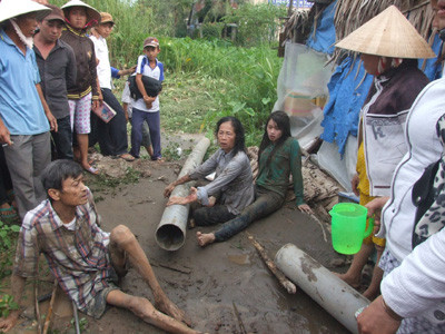 Vợ chồng bà Màu và con gái ở miệng ống bơm cát 