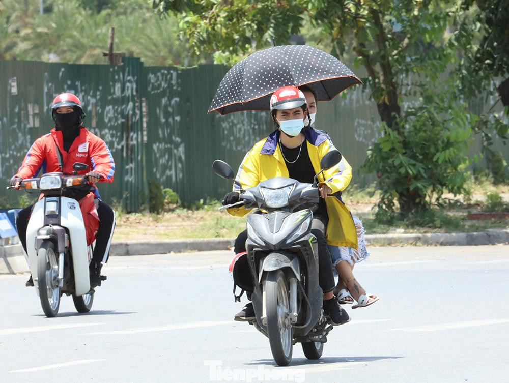 Có người đi trên đường mang theo cả ô che nắng