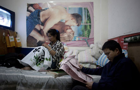 Niu Song, 33 tuổi, đọc báo, trong khi vợ Zhao Ansheng, 32 tuổi, khâu vá trong căn phòng “ngầm” gần bắc Đường vành đai 3 ở Bắc Kinh